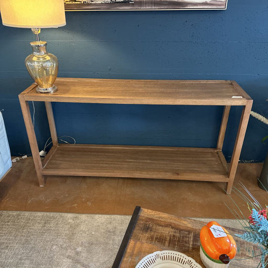 Wooden console table against a blue wall with a lamp on top