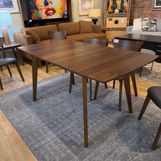 Wooden dining table in a room with chairs and a rug
