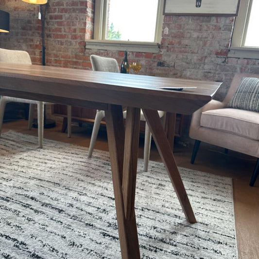 Wooden dining table in a room with brick walls and a rug.
