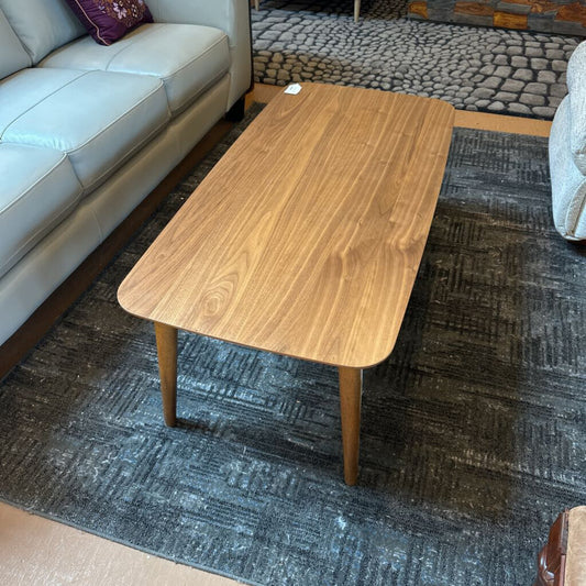 Wooden coffee table in a living room setting with a gray sofa and patterned rug.