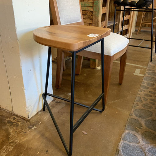 Wooden stool with black metal legs in a rustic setting