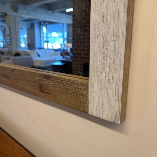 Wooden-framed mirror with a blurred indoor setting reflection