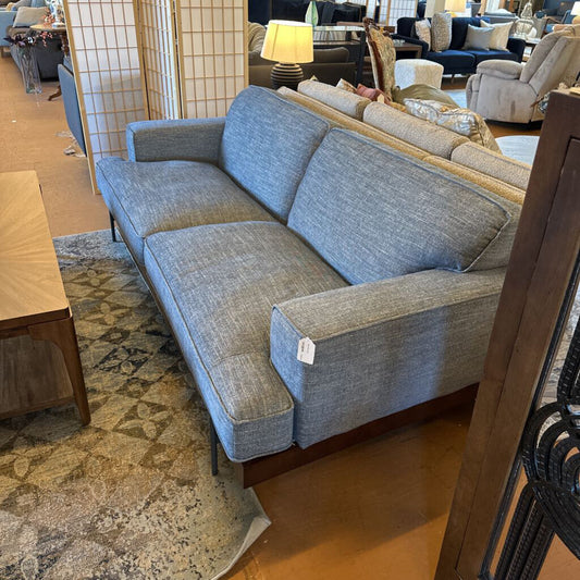 Gray sofa in a furniture store setting with other furniture items around.