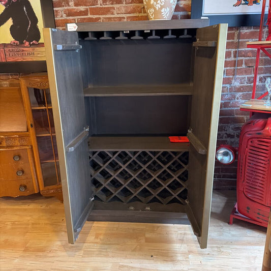 Wine cabinet with open door revealing wine racks against a brick wall.