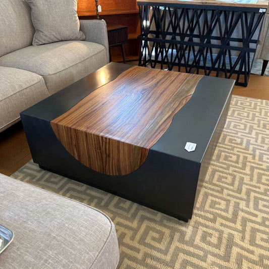 Wooden coffee table with black base in a living room setting
