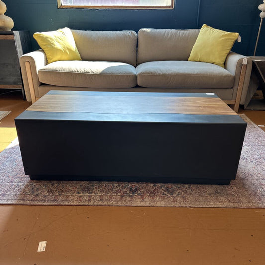Gray sofa with yellow cushions and a black and wooden coffee table in a room.