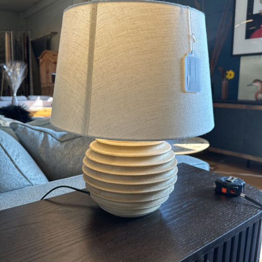 Beige table lamp with textured base on a dark surface
