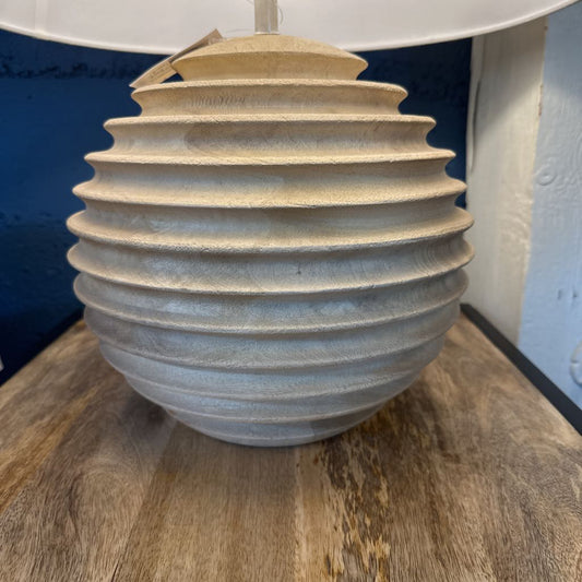 Textured ceramic vase on a wooden surface with a blue wall in the background