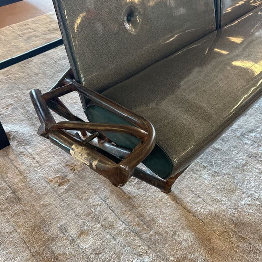 Metal bench with a worn armrest on a stone floor