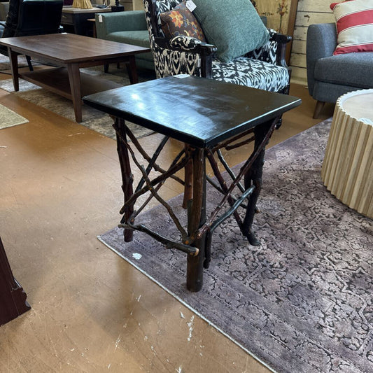 Small black table with rustic legs in a room with furniture and decor.