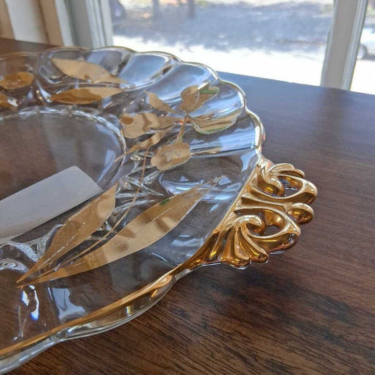 Decorative glass dish with gold leaf design on a wooden table