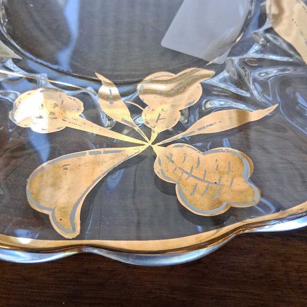 Decorative glass dish with gold leaf design on a wooden surface