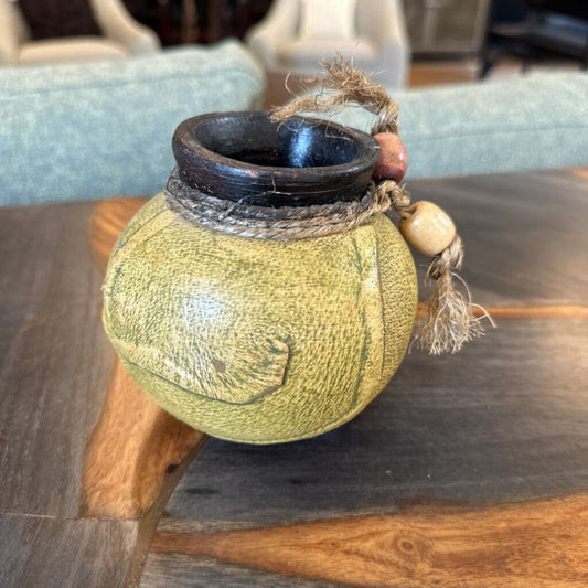 Decorative spherical vase with textured surface and string decoration on a wooden table.