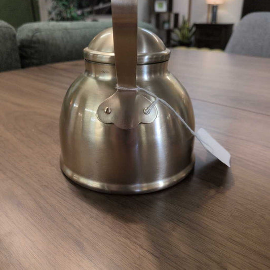 Silver kettle on a wooden table with a tag attached