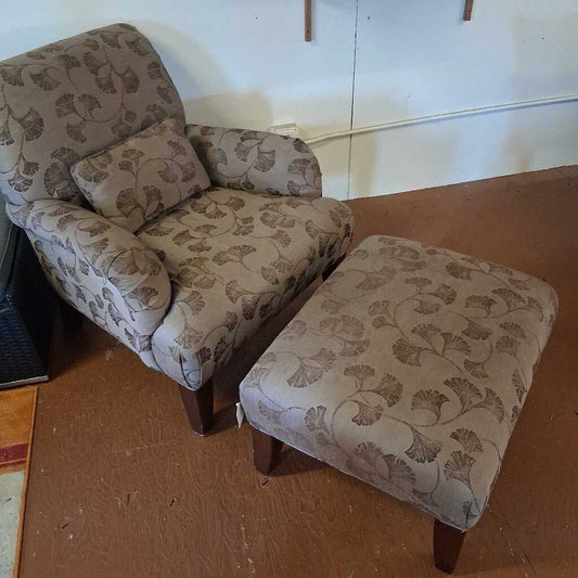 Patterned armchair and ottoman on a wooden floor with a white wall background
