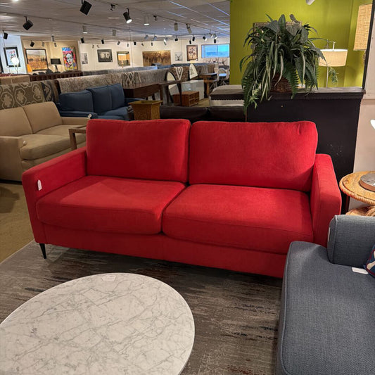 Red sofa in a furniture store with other couches and decor items.