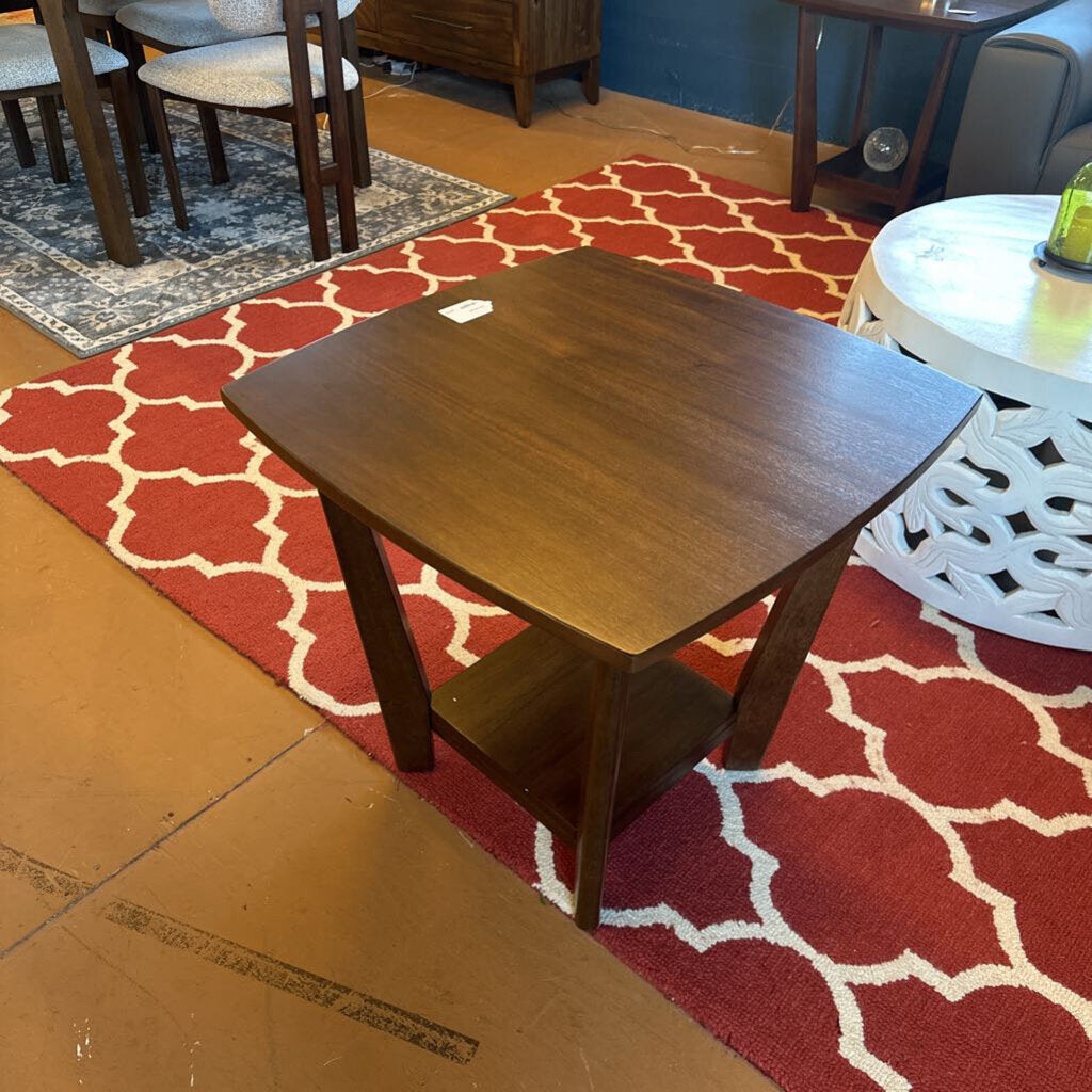 Wooden side table on a red patterned rug with a room in the background