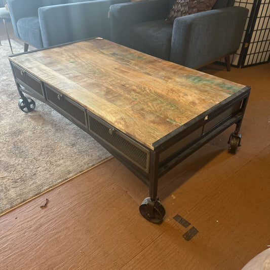Wooden coffee table with metal frame on wheels in a room setting