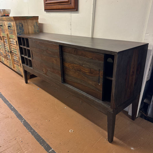 Dark wooden sideboard with shelves against a white wall.