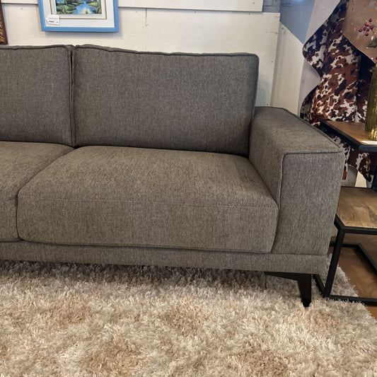 Gray sofa in a room with a wooden floor and a small table.