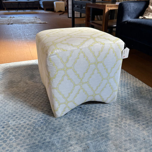 Patterned ottoman on a carpeted floor in a room with furniture.
