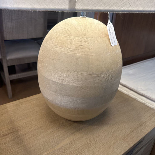 Wooden egg-shaped object with a tag on a wooden surface