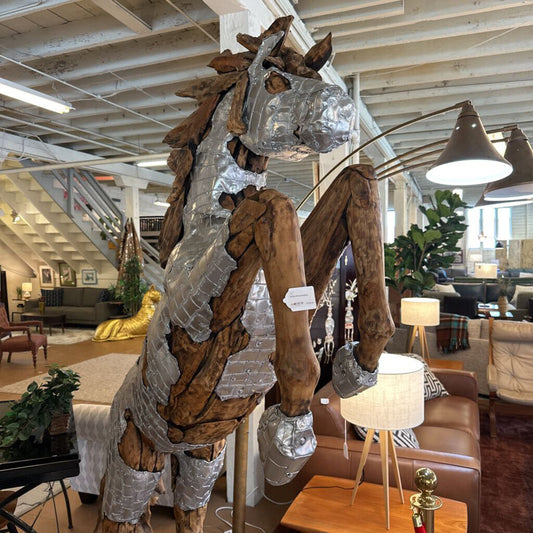 Large metallic horse sculpture in a showroom setting with furniture and decor.