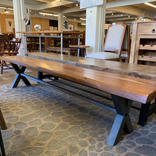 Long wooden bench with metal legs in a furniture store setting
