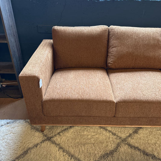 Brown sectional sofa against a blue wall on a patterned rug