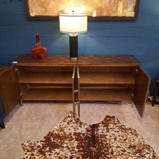 Wooden sideboard with a lamp and decorative items against a blue wall.
