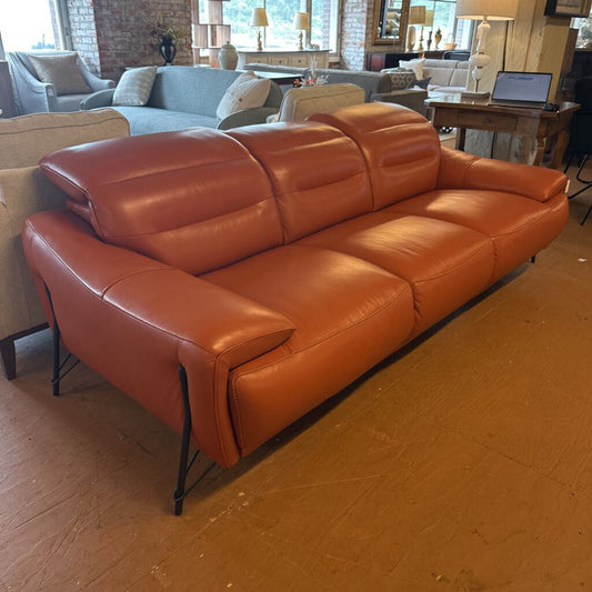 Orange leather sofa in a room with other furniture and decor.
