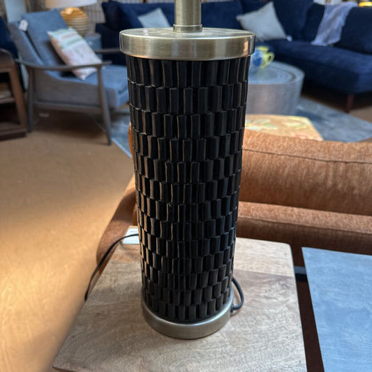 Black textured table lamp on a wooden surface with a living room background