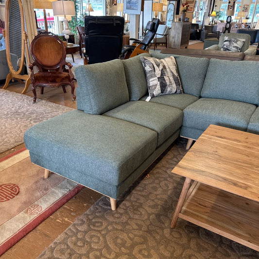 Gray sectional sofa in a room with wooden coffee table and chairs.