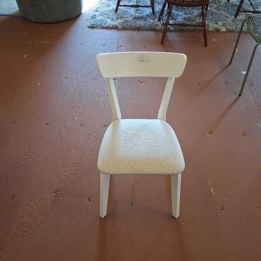 White chair on a wooden floor with a rug in the background