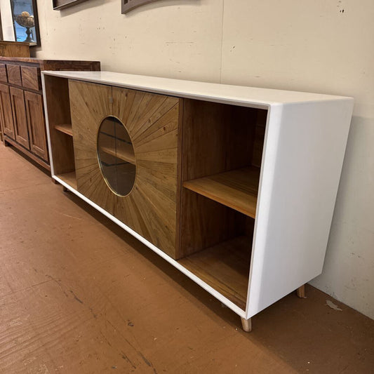 White and wooden sideboard with circular design on a wooden floor.