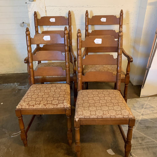 Set of wooden chairs with patterned seats in a storage area.