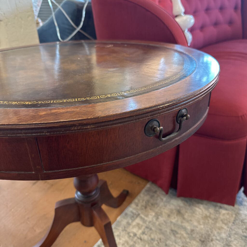 Wooden side table with a red upholstered chair in the background
