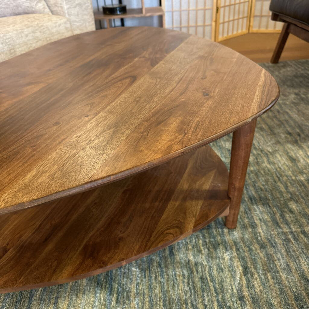 Wooden coffee table in a room with a rug and partial view of furniture.