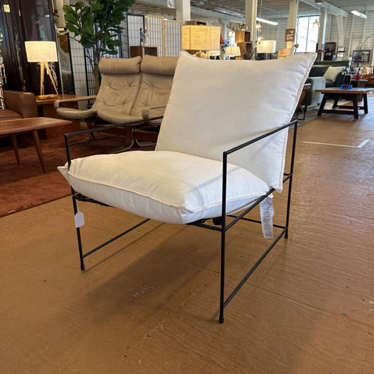 White cushioned chair with black metal frame in a showroom setting