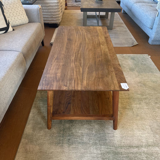 Wooden coffee table in a room with furniture and flooring samples.