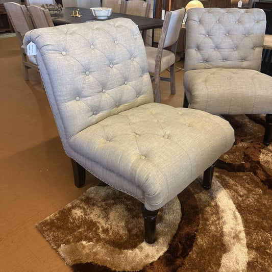 Two upholstered chairs in a room with a table and chairs in the background.