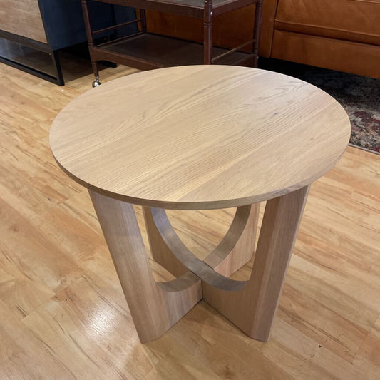 Wooden side table on a wooden floor with furniture in the background