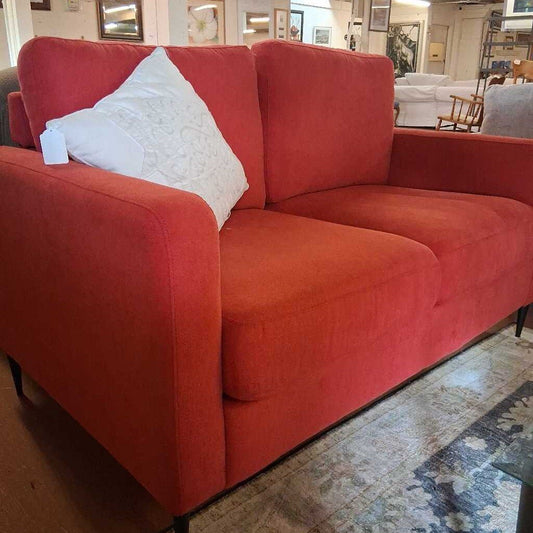 Red sectional sofa with a white pillow in a showroom setting