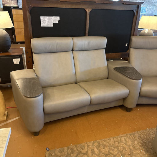 Beige leather sofa with cup holders in a showroom setting