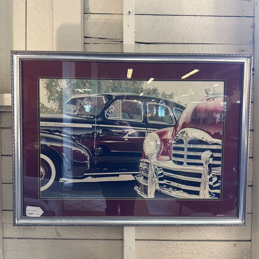 Framed picture of a classic car on a wooden surface