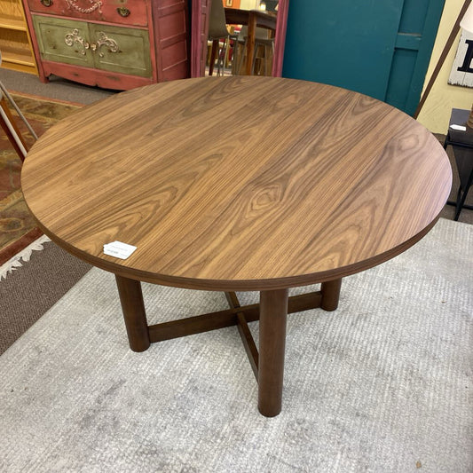 Round wooden table with a label on a gray carpeted floor