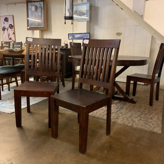Wooden chairs in a room with tiled walls and framed pictures.