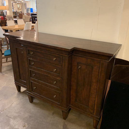 Wooden sideboard with multiple drawers and a cabinet door in an indoor setting.