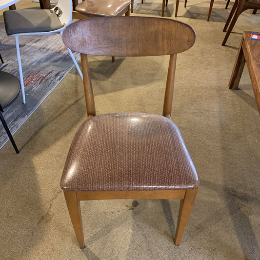 Wooden chair with a brown cushioned seat on a carpeted floor.