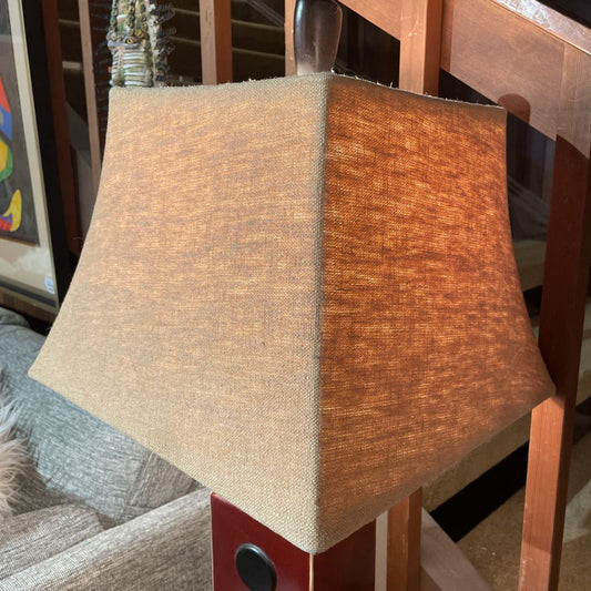 Textured lampshade on a wooden base with a blurred background
